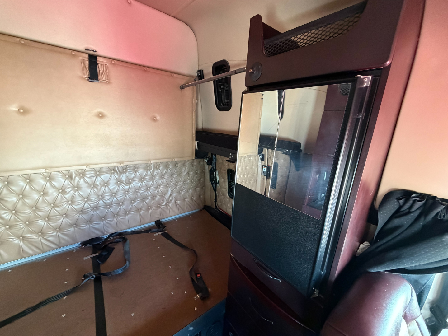 Interior sleeper cab of a 2020 Western Star 4900 showing quilted side panel, sleeper door and storage net with a mirror visible.