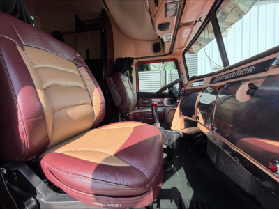 Trucks cab interior showing steering wheel and dashboard in a Western Star 4900 sleeper cab with tan and maroon leather seats.