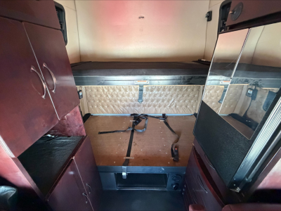 Interior of a Western Star 4900 sleeper cab showing back wall with diamond-plate bunk area, storage cabinets on left, mirrored panel on right, and bed straps.