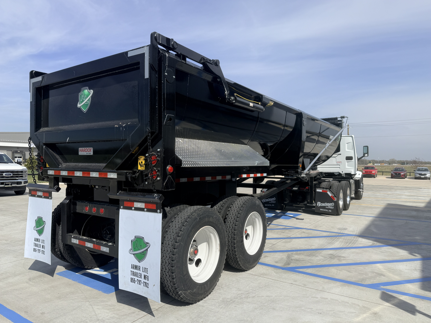 Dump trailer showing Armor Lite SHD 28/48 1/4 frame single point with dual rear axles and black container.