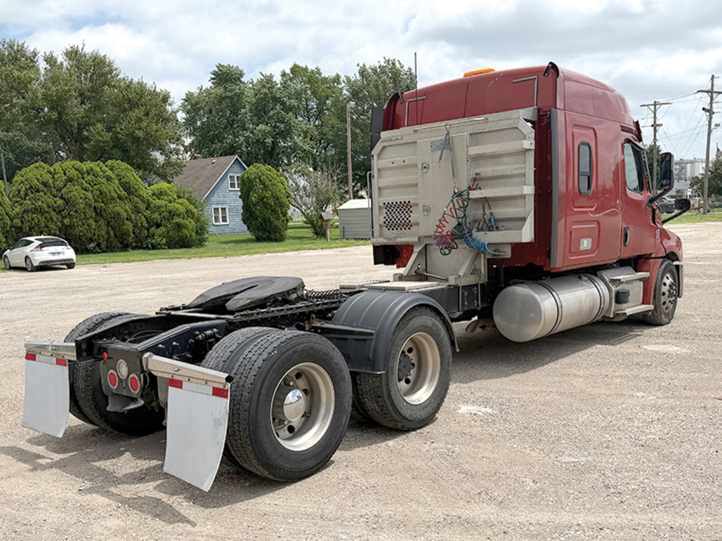 Truck rear view showing fifth wheel, dual rear axles, and red cab of a Freightliner Cascadia126 with aluminum fuel tanks and exposed chassis.