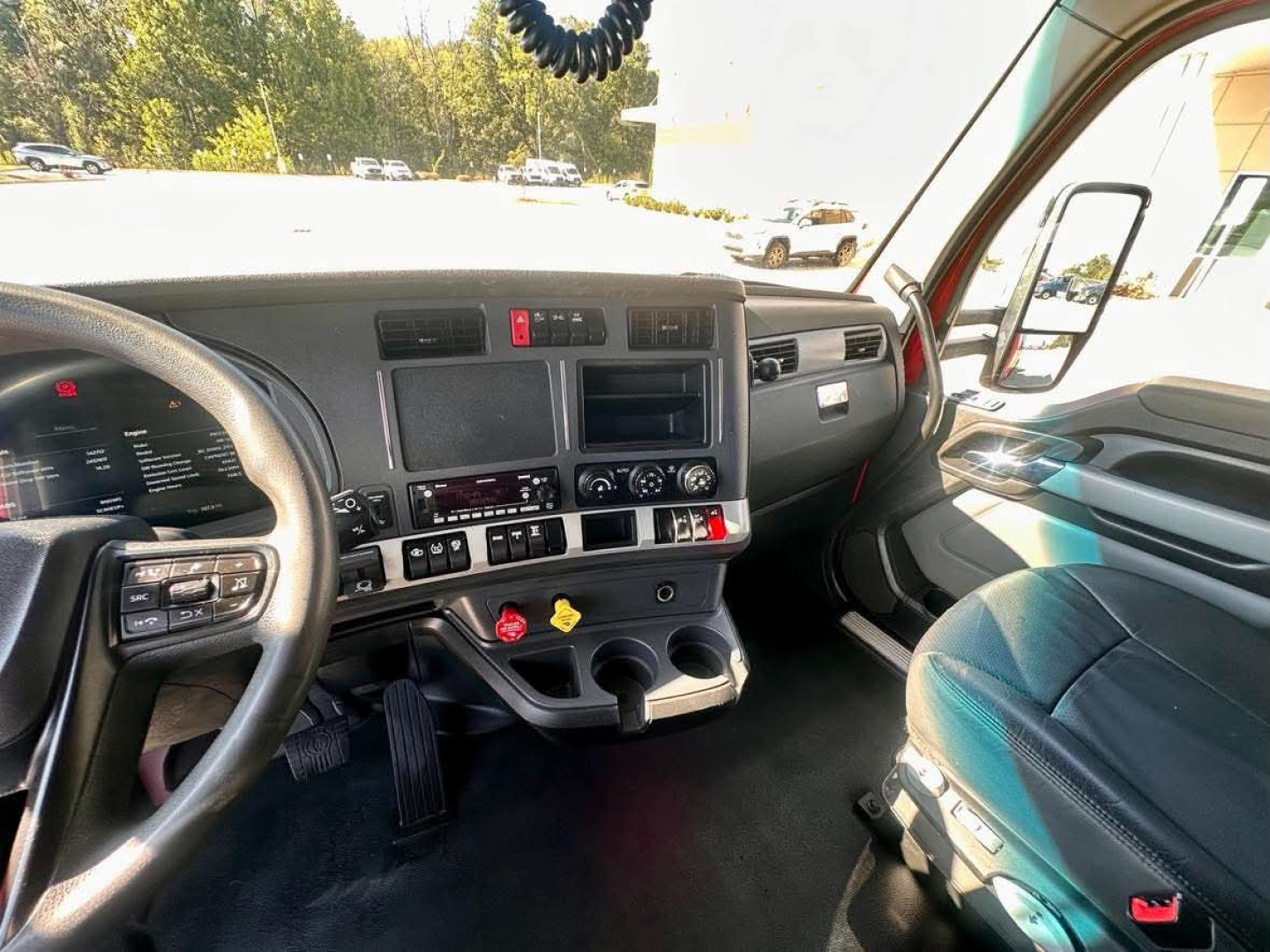 Kenworth T680 truck interior dashboard view showing steering wheel, center console, ignition area, and driver seat.