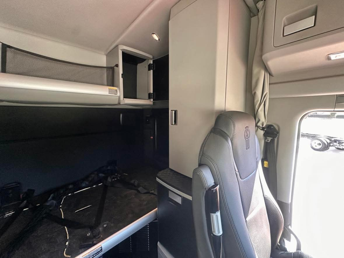 Cab interior of a Kenworth truck showing sleeper berth and overhead storage compartments.