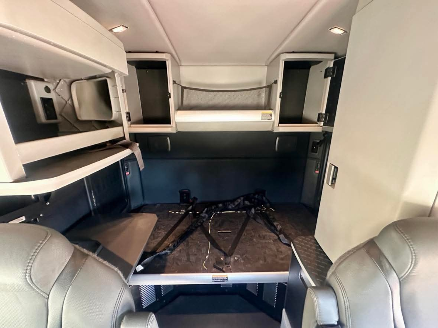 Kenworth T680 sleeper cab interior cargo area with sleeper bunks and storage cabinets, view from front seating area.