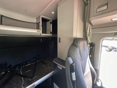 Cab interior of a Kenworth truck showing sleeper berth and overhead storage compartments.