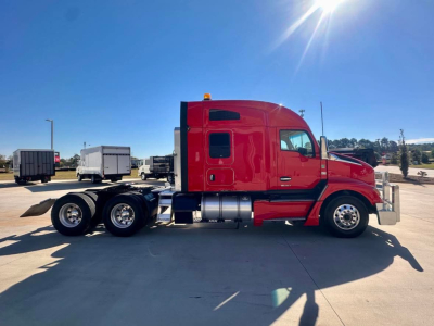 Kenworth T680 truck side view, red cab, tandem rear axles, fuel tanks, chrome bumper, clear sky