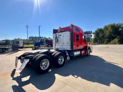 Kenworth T680 conventional sleeper truck rear three-quarter view showing red cab, white service box, dual rear axles and fuel tanks.