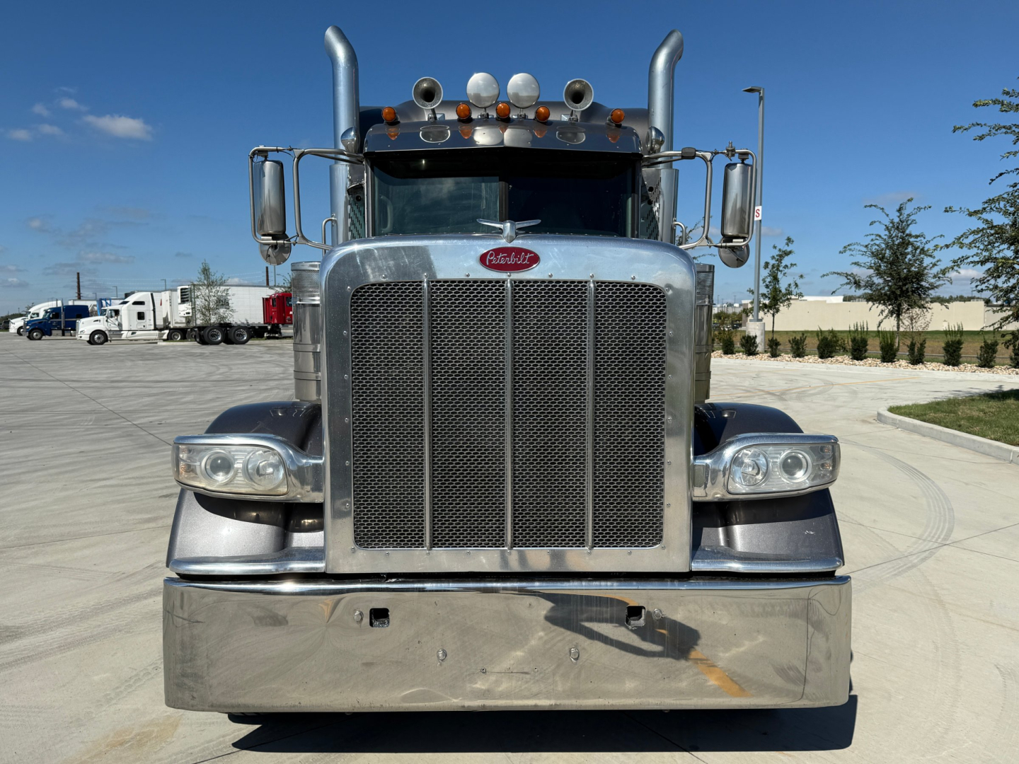 Peterbilt 389 front view showing large grille with chrome bumper and dual exhaust stacks.