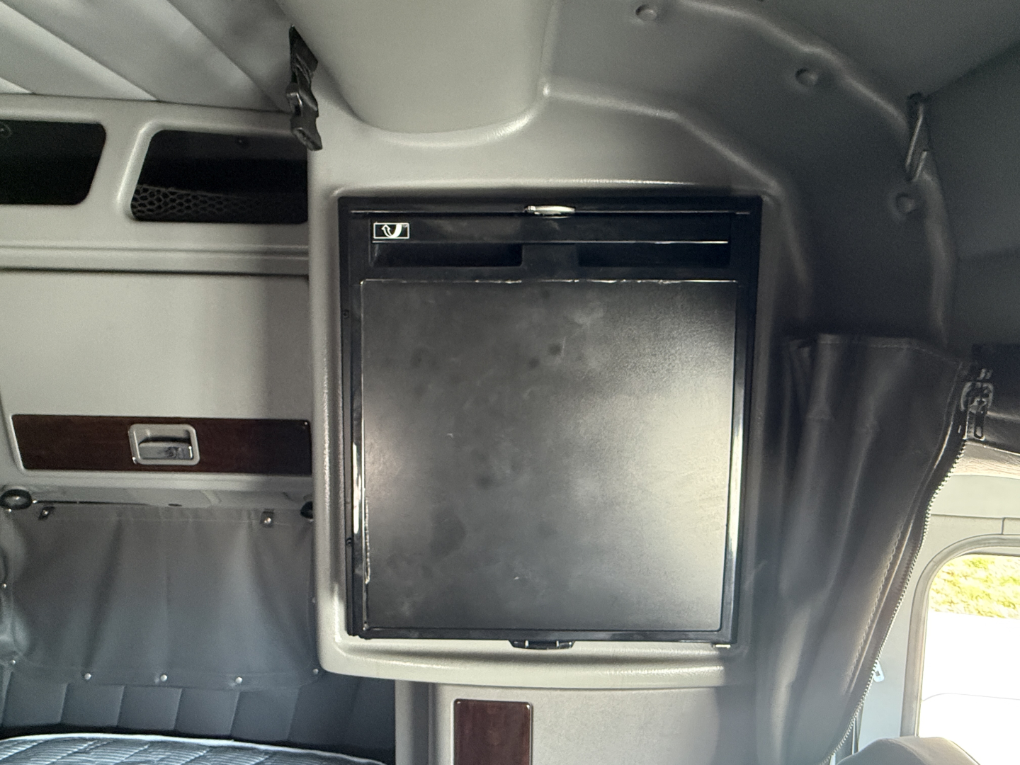 Peterbilt 389 cab interior with a small black refrigerator door mounted in sleeper area.