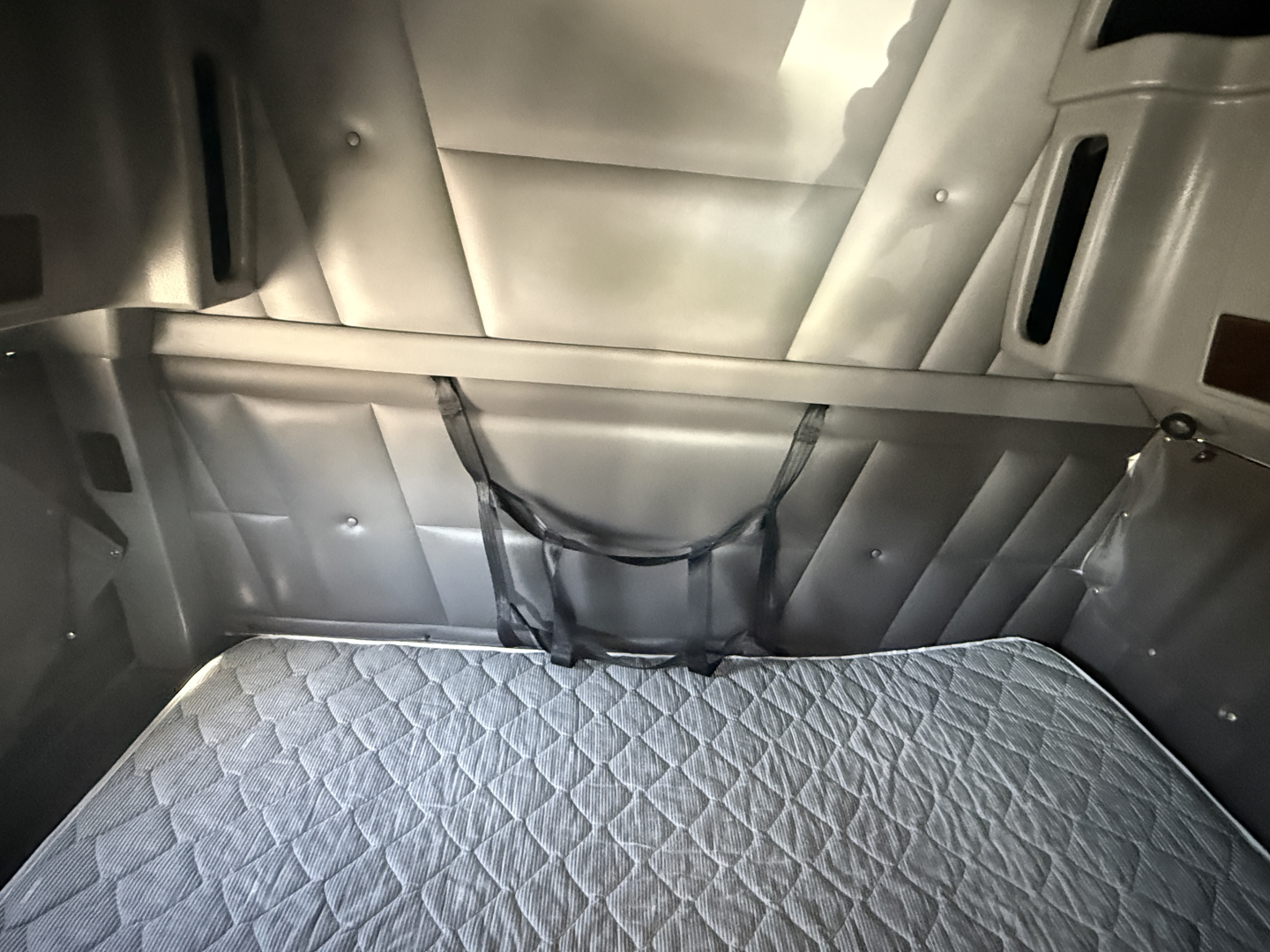 Peterbilt 389 sleeper cab interior cargo area with quilted bed and cargo nets, cargo area in a truck sleeper.