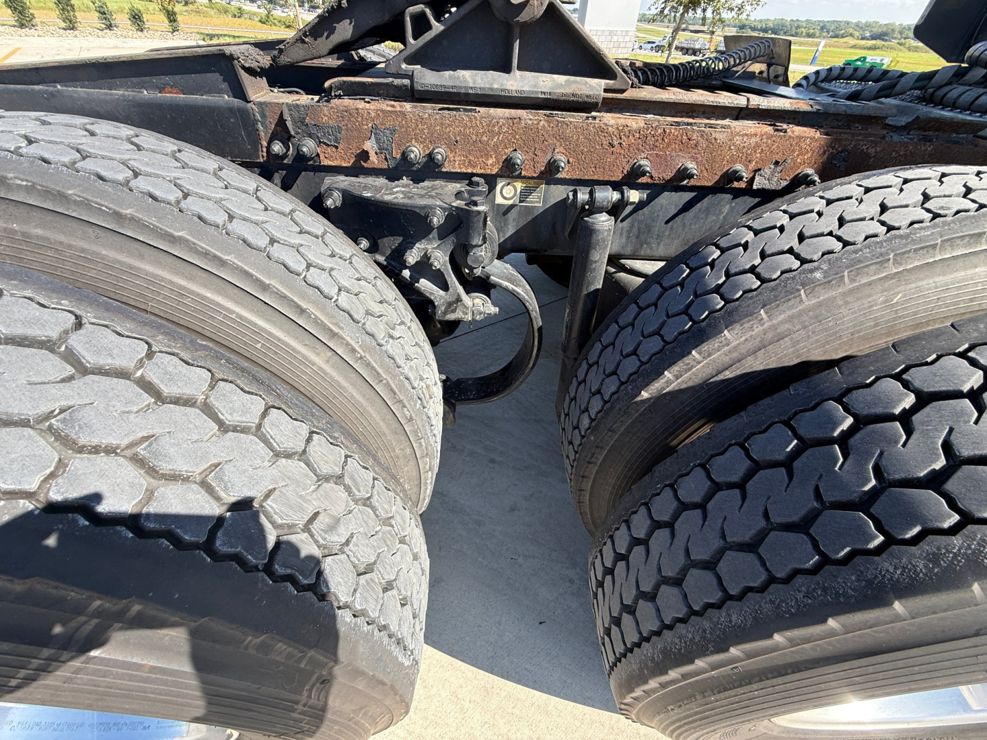 Peterbilt 389 truck chassis with dual rear axles and tires in view; rusty frame and suspension components visible; no cab or engine shown.