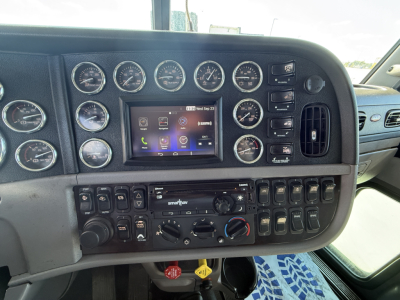 Dashboard of a 2020 Peterbilt 389 conventional sleeper truck showing multiple gauges, a central touchscreen display, and various switches.