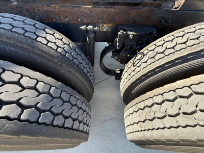 Viewed from between dual rear wheels of a Peterbilt 389 tractor showing drivetrain hanger and suspension components. No legible text visible.