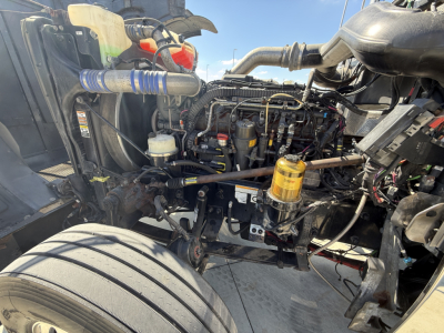 Peterbilt 389 engine bay visible with exposed components and hoses; fuel/air system lines, filters, and electrical harnesses in view.