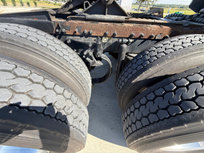 Peterbilt 389 truck chassis with dual rear axles and tires in view; rusty frame and suspension components visible; no cab or engine shown.