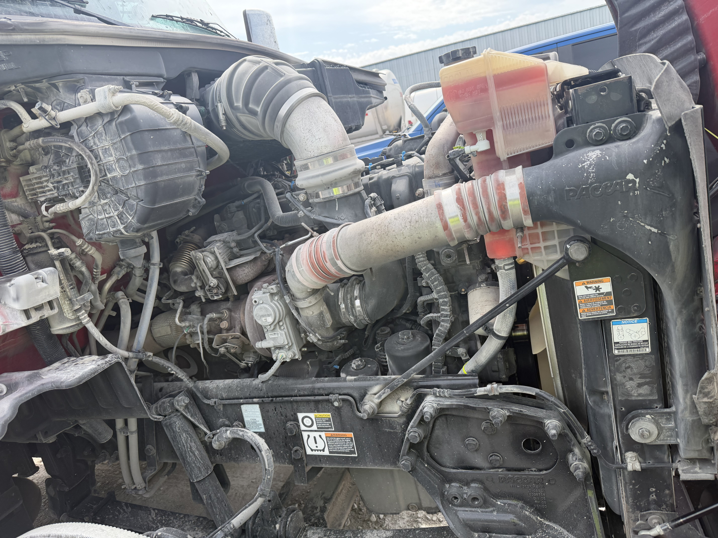 Peterbilt 579 engine bay showing coolant reservoir, air intake hose, and front radiator area.