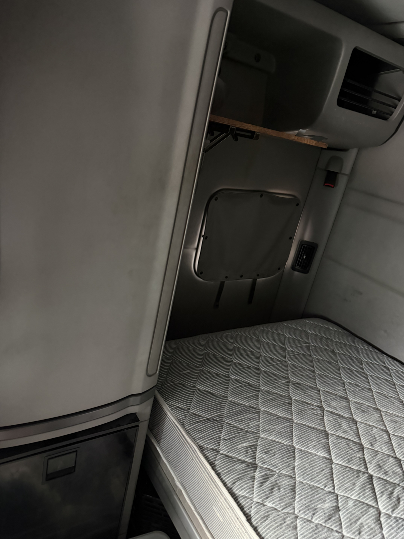 Peterbilt 579 truck cab interior showing sleeper berth with quilted mattress and side storage panel