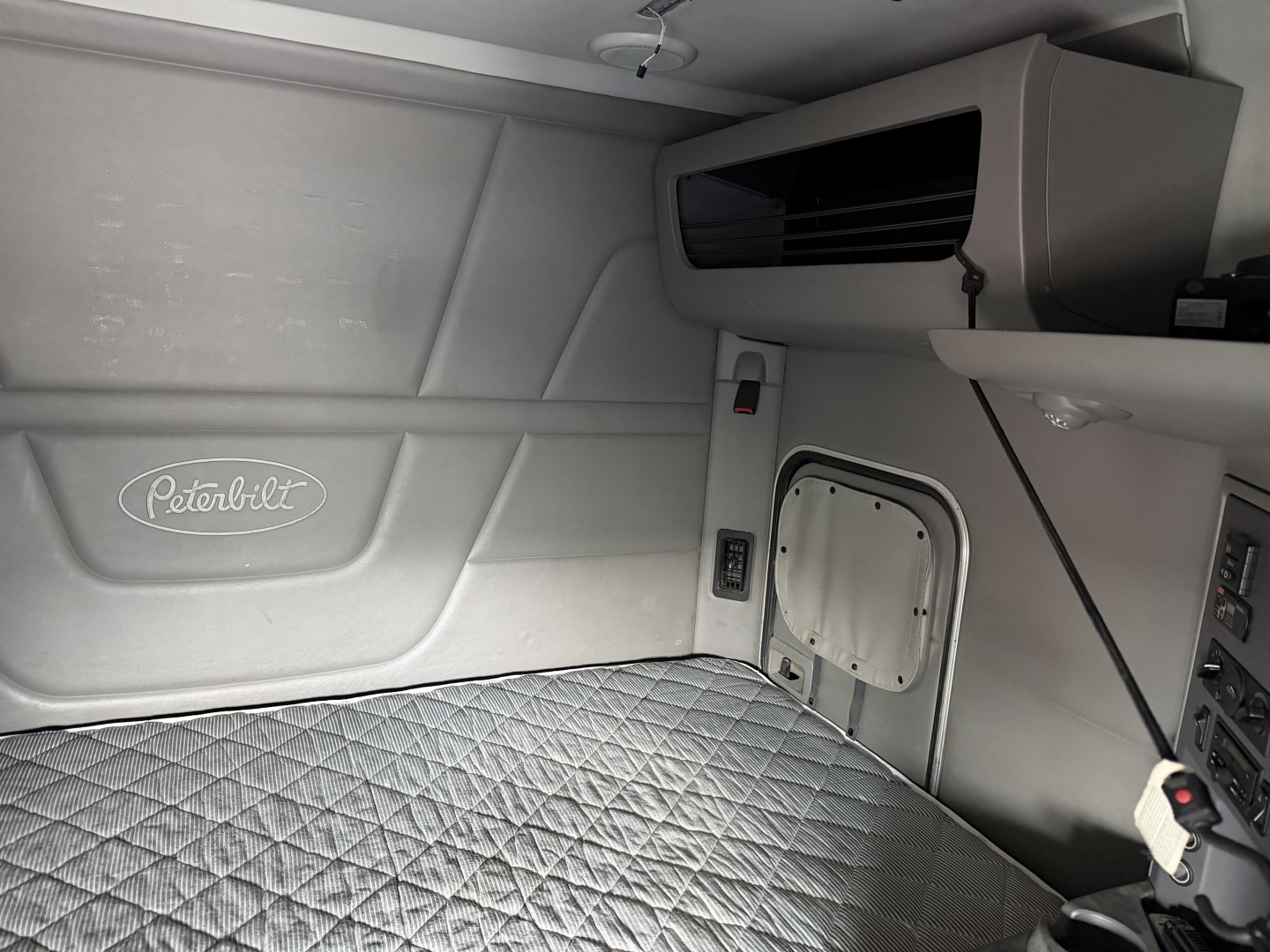 Peterbilt 579 sleeper cab interior view showing side panel with Peterbilt logo and storage console.