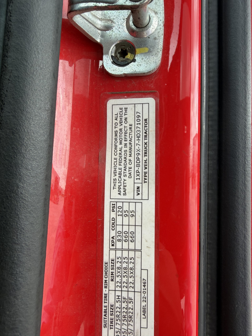 Vehicle identification and specification label on a red Peterbilt 579 door frame showing VIN 1XPBDP9X7HD371097 and weight/axle data.