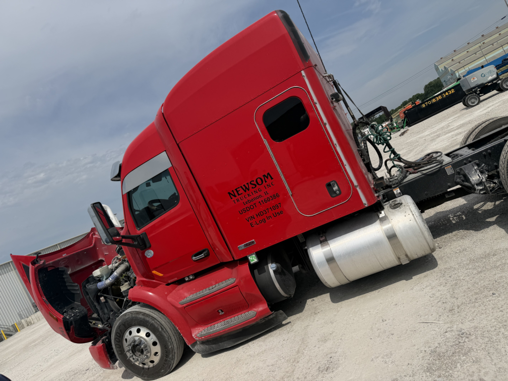 Peterbilt 579 tractor cab in red with open hood and exposed engine area, side fuel tank visible.