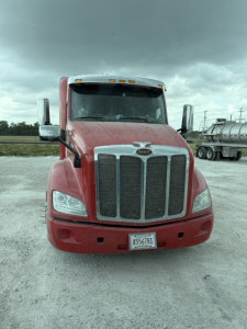 Peterbilt 579 truck front view in red paint with large chrome grille, headlights, side mirrors, and license plate A556781; VIN plate not visible.