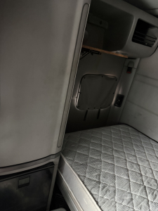 Peterbilt 579 truck cab interior showing sleeper berth with quilted mattress and side storage panel