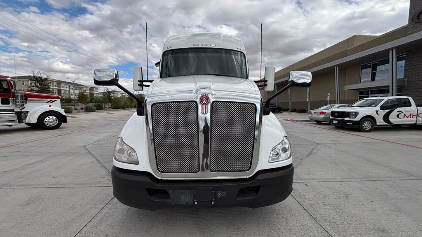 Front view of a white Kenworth T680 truck showing large mesh grille, headlights, and side mirrors.