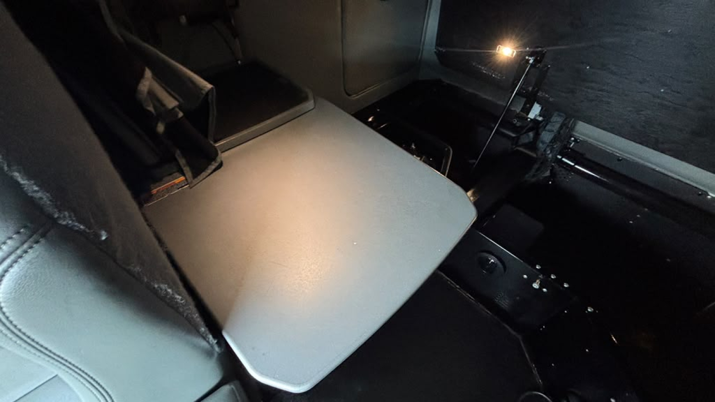 Interior of a Kenworth truck cab with a fold-out bunk table and dark control panels visible.