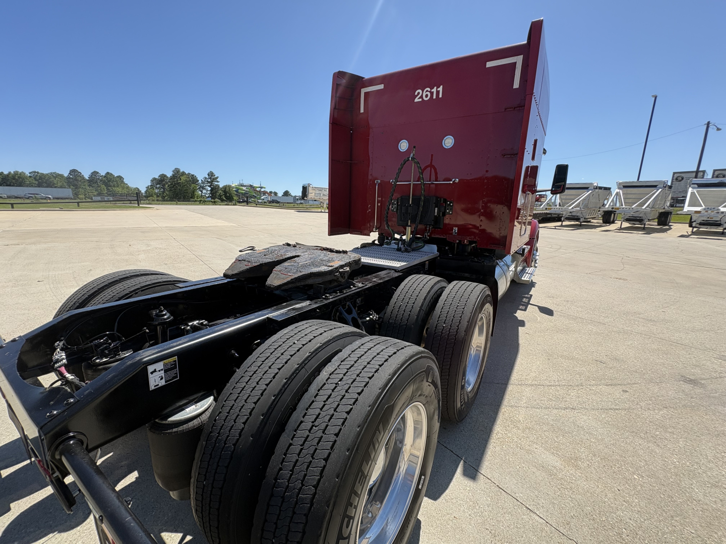 Peterbilt 579 tractor rear view showing fifth wheel and dual rear axles with red sleeper cab and chassis.
