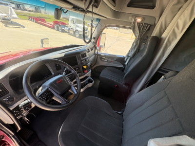 Peterbilt 579 truck cab interior dashboard and steering wheel view showing driver seat and passenger seat, with overhead sun visor and center console.