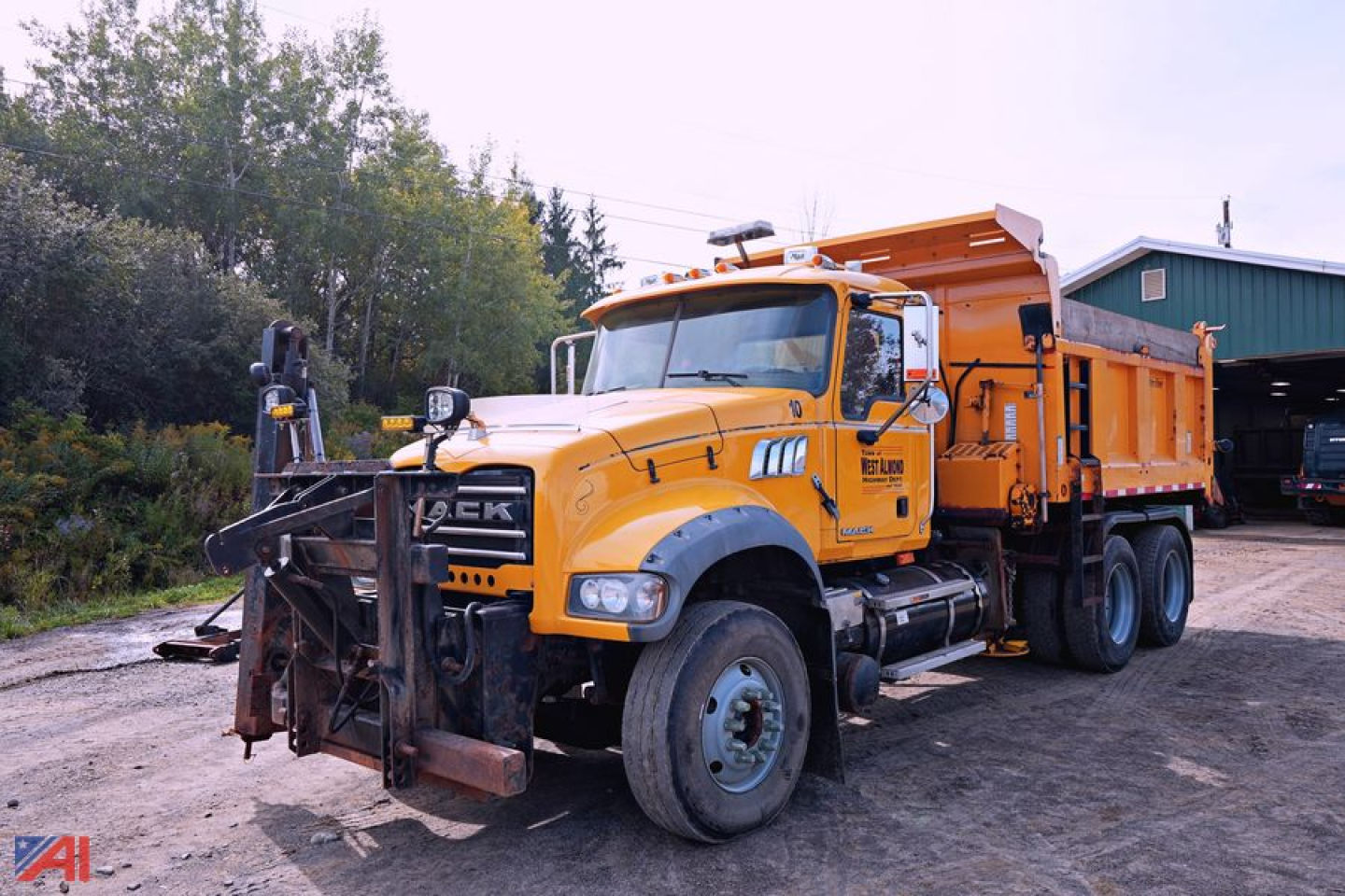 Dump truck showing Mack GU713 Granite with orange plow and dump bed in service view.