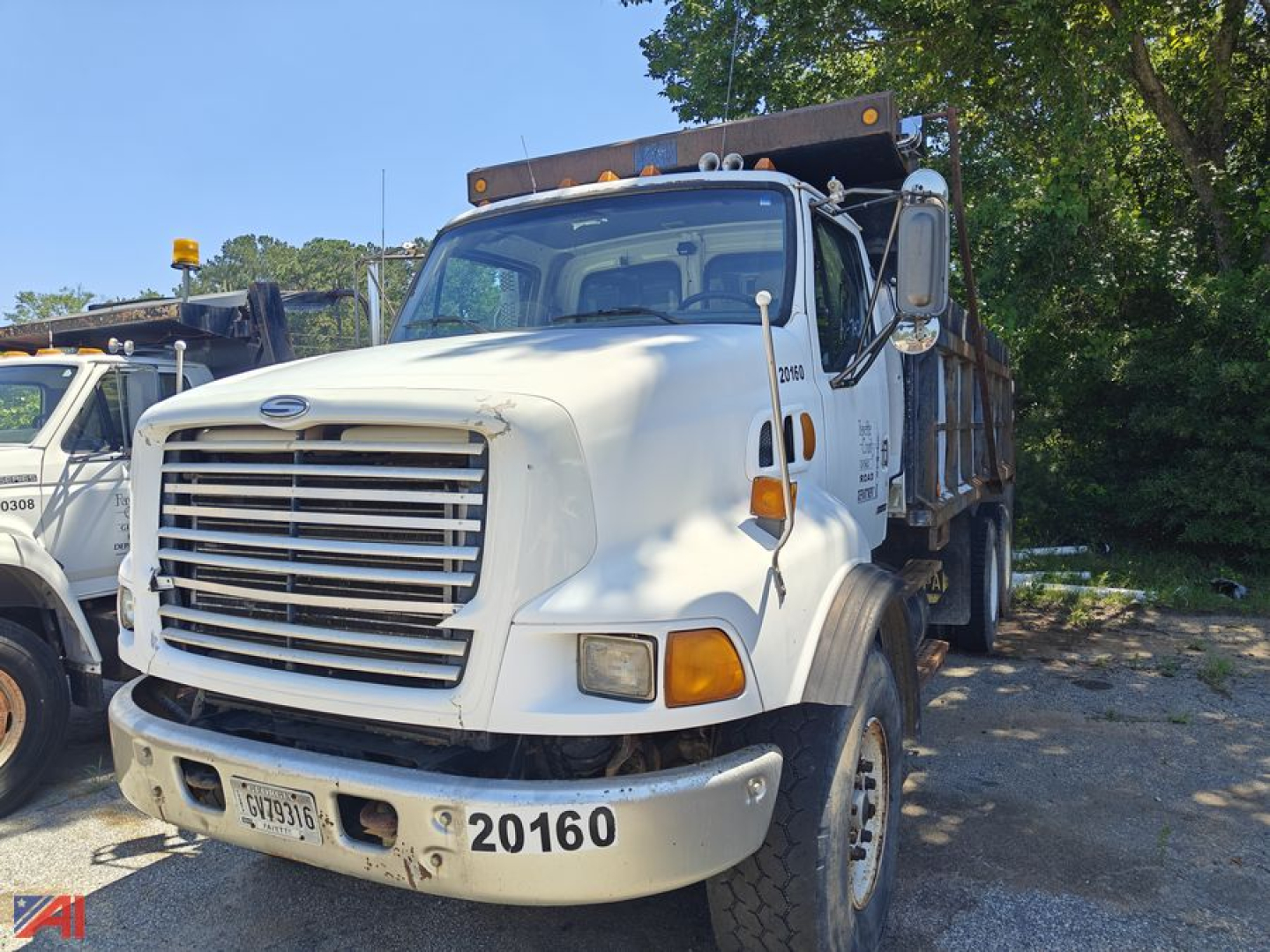 Dump truck front-left view showing Sterling LT9500 series with white cab and dump bed, grille, headlights, and front bumper with '20160' number on it.