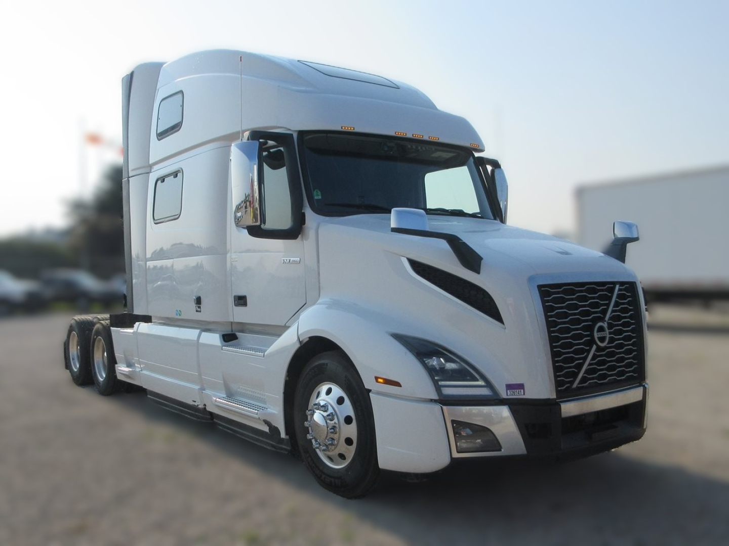 Volvo VNL64T860 sleeper tractor in white, front-left view showing chrome grille, aerodynamic cab with high roof, dual rear axles, and side mirrors.