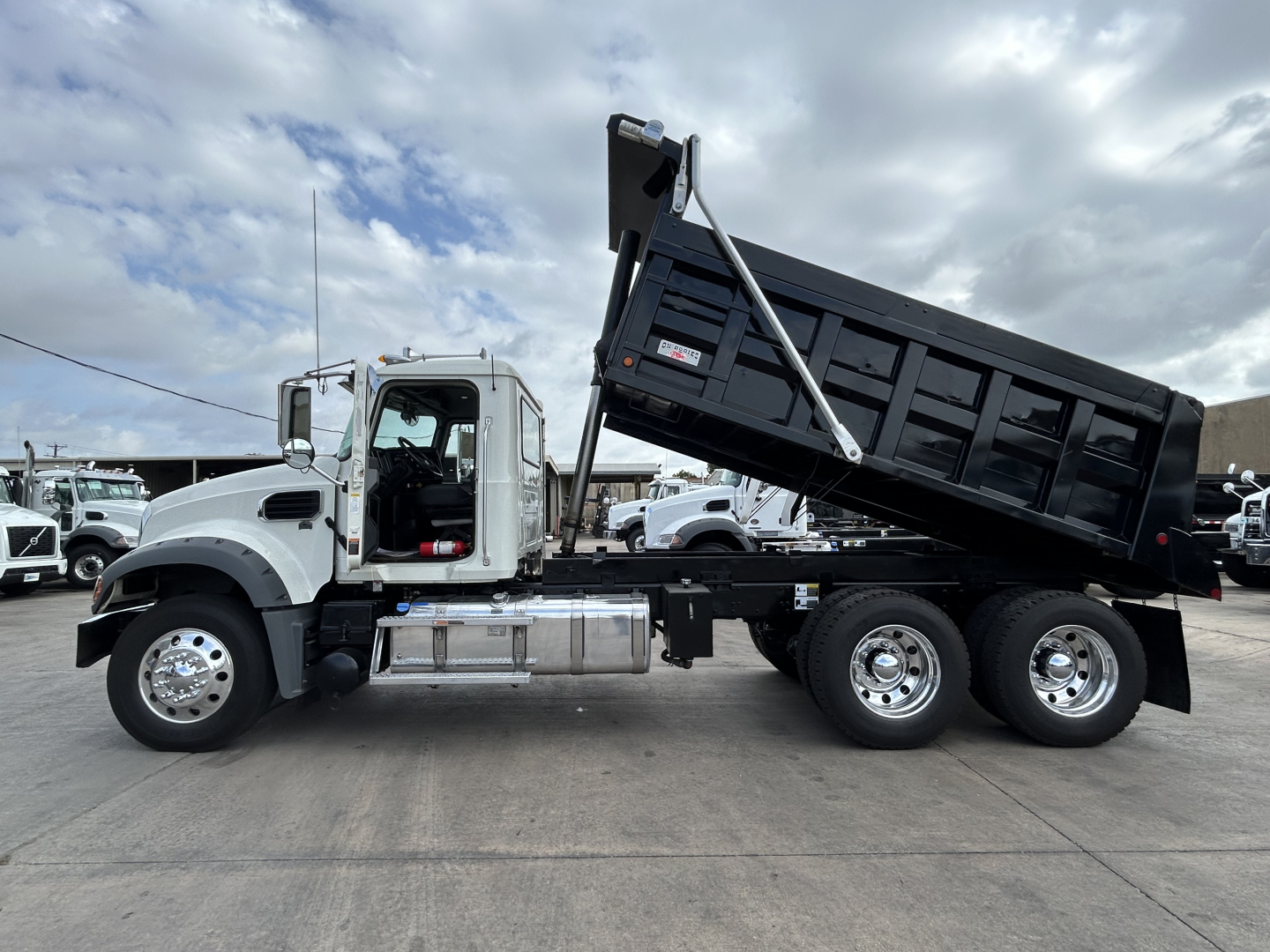 Dump truck with raised dump bed showing Mack GR64F chassis and dual rear axle.
