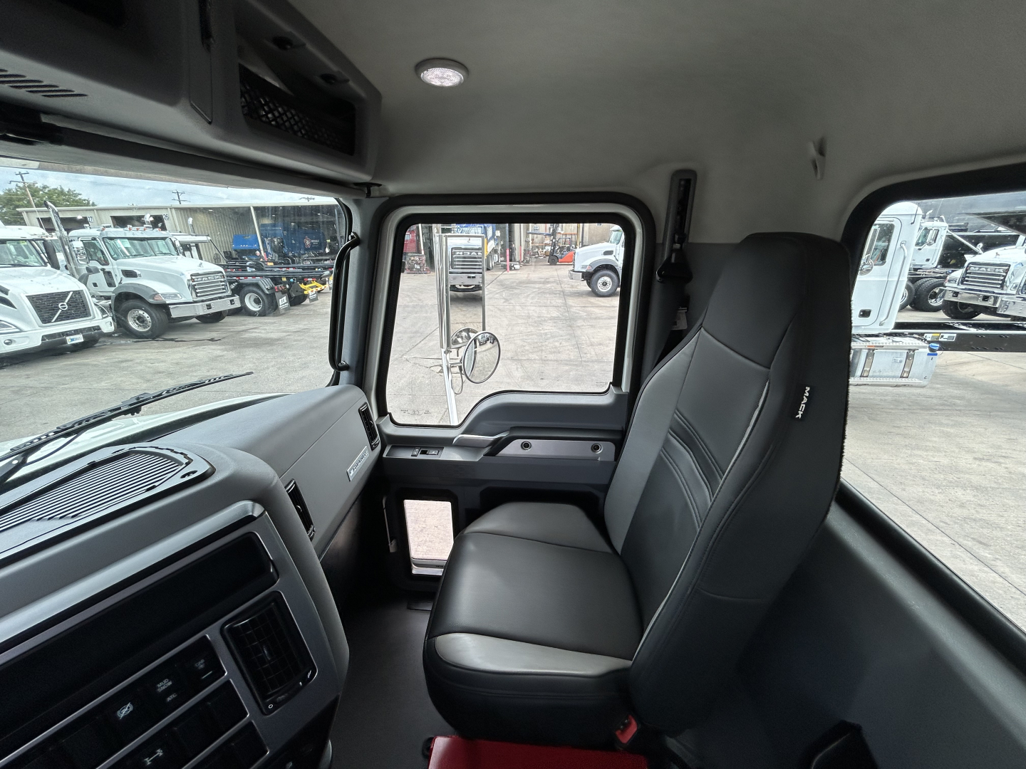 Truck cab interior showing front passenger seat and dashboard of a 2025 Mack GR64F dump truck.