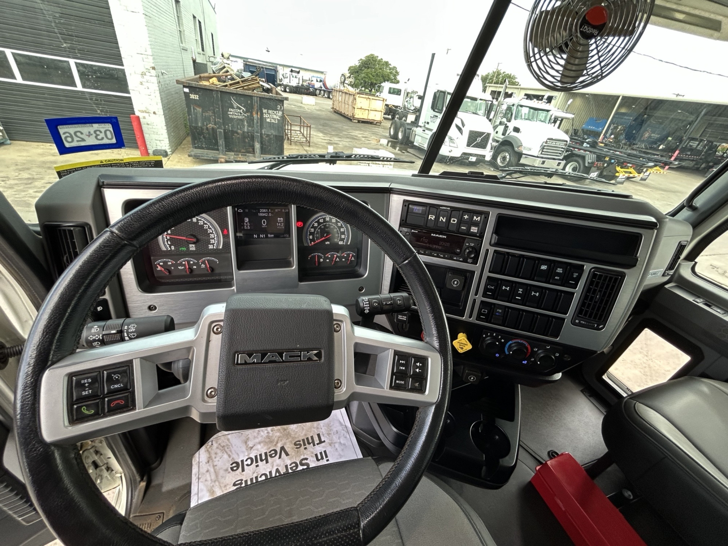 Mack GR64F truck dashboard and steering wheel view showing steering wheel with Mack logo and instrument cluster