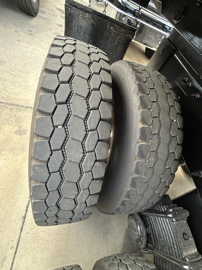 Dual rear tires on a Mack GR64F dump truck showing tread pattern and side by side positioning.