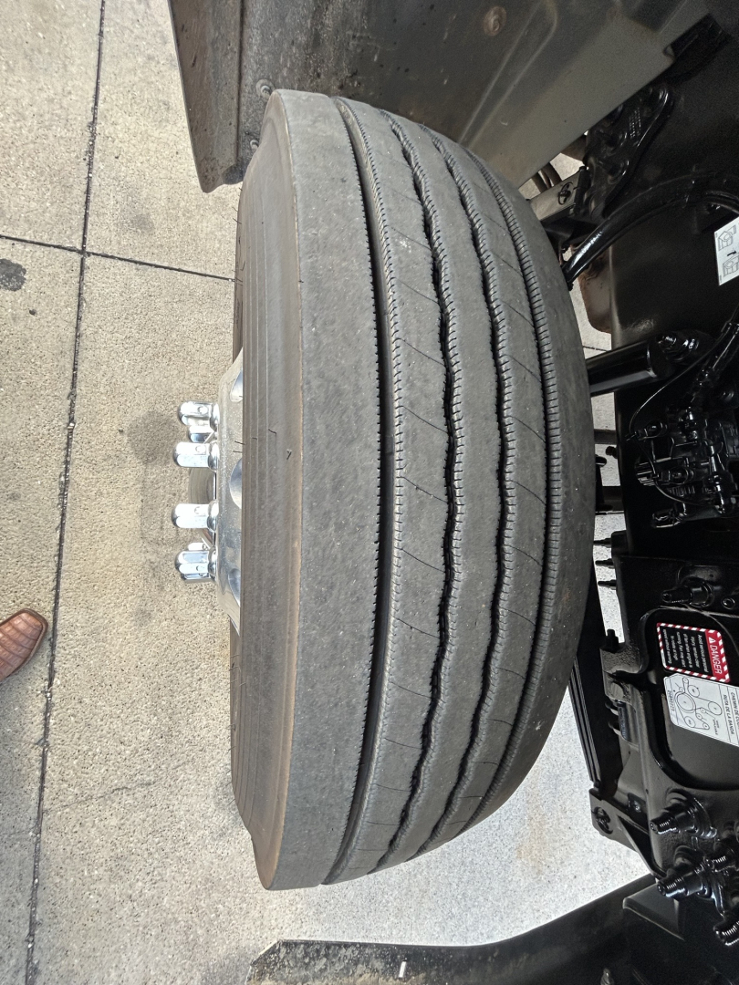 Mack GR64F wheel/view showing single steering or drive axle with dual treads and tire inflation area, plate area, and chassis components visible.