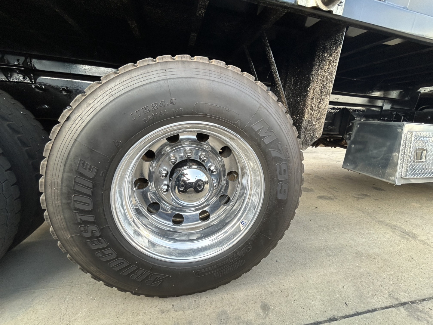 Wheel and tire of Mack GR64F dump truck showing Bridgestone tire with chrome rim and hub area.