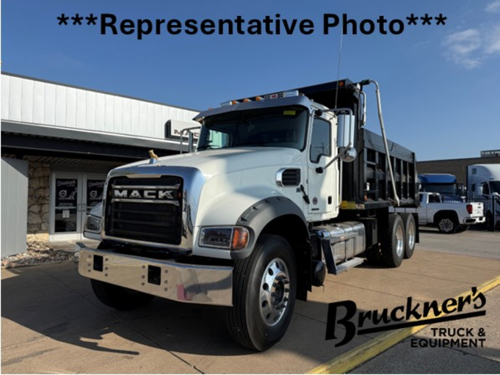 Mack GR64F dump truck in-service showing front grille with MACK badge, white cab, dump bed, daytime. Representative photo with Bruckner's Truck & Equipment watermark.