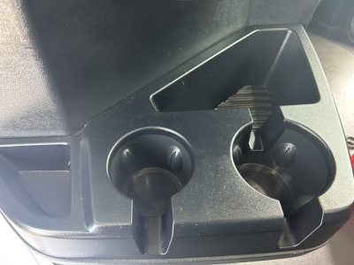 Cab center console area of a 2025 Mack GR64F showing cup holder slots and a small storage opening.