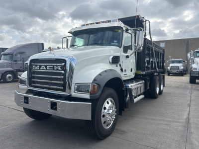 Mack GR64F Dump truck showing front grille with Mack lettering, chrome bumper, white cab, and dump bed.