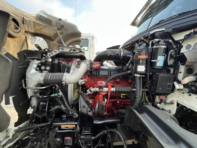 Mack GR64F engine bay with turbocharger and red engine block visible; various hoses, wiring harnesses, radiator hoses, and components in view.