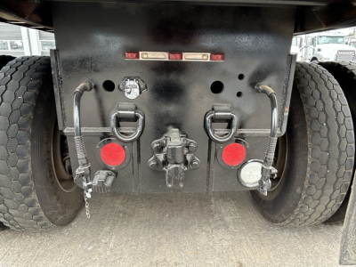 Rear view of Mack GR64F chassis showing tow hooks, lights, and connection points with two red reflectors, fuel/filler cap, and hydraulic/air lines.