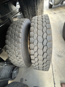 Pair of tires on Mack GR64F dump truck showing tread pattern and wheel assembly.