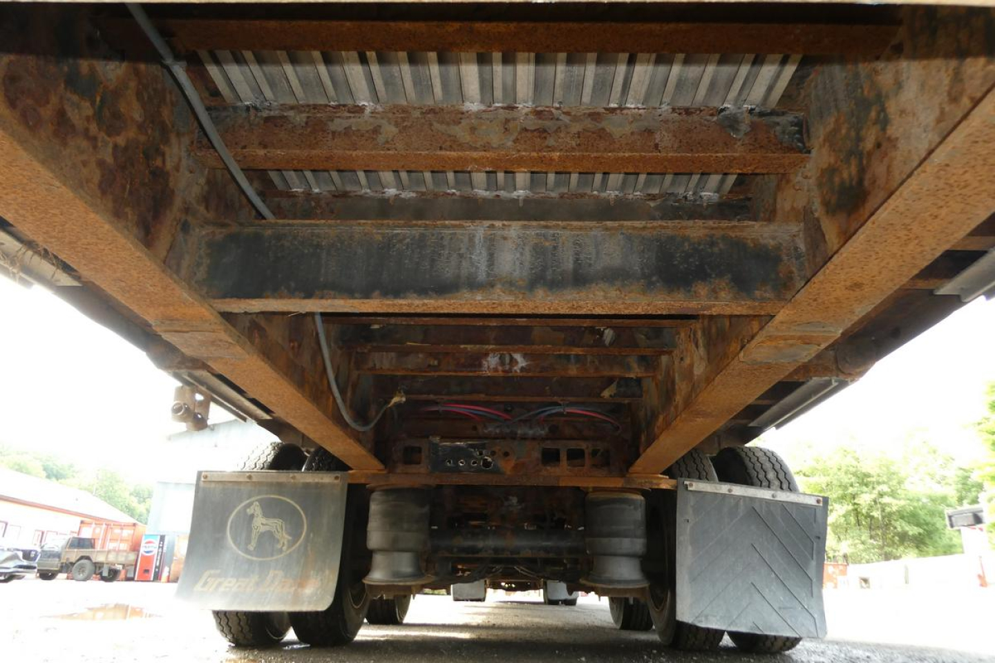 Understructure of a used drop deck trailer showing steel frame, suspension, and wheels