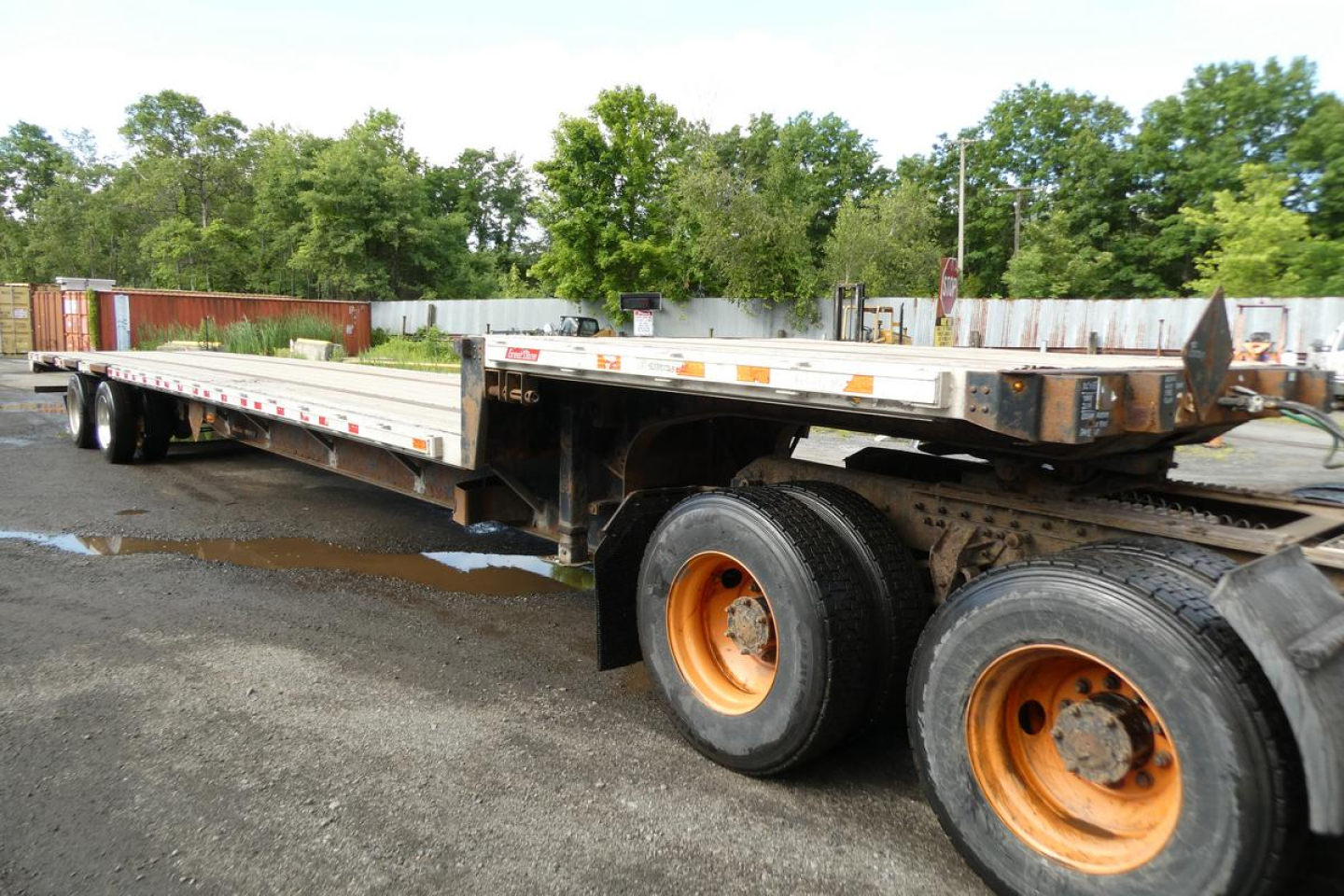 Great Dane FLD002400053 trailer in yard showing dual rear axles with orange rims and long flatbed deck.