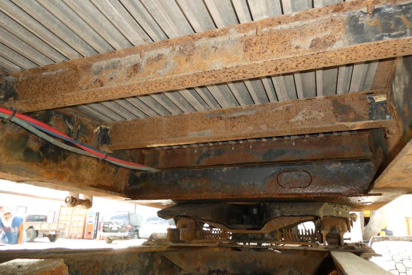 Great Dane trailer undercarriage showing rusted steel frame, cross members, and caster wheel assembly with cables running along the side.