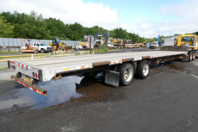 Great Dane FLD002400053 trailer flatbed in service showing triple-axle configuration and rear lights.