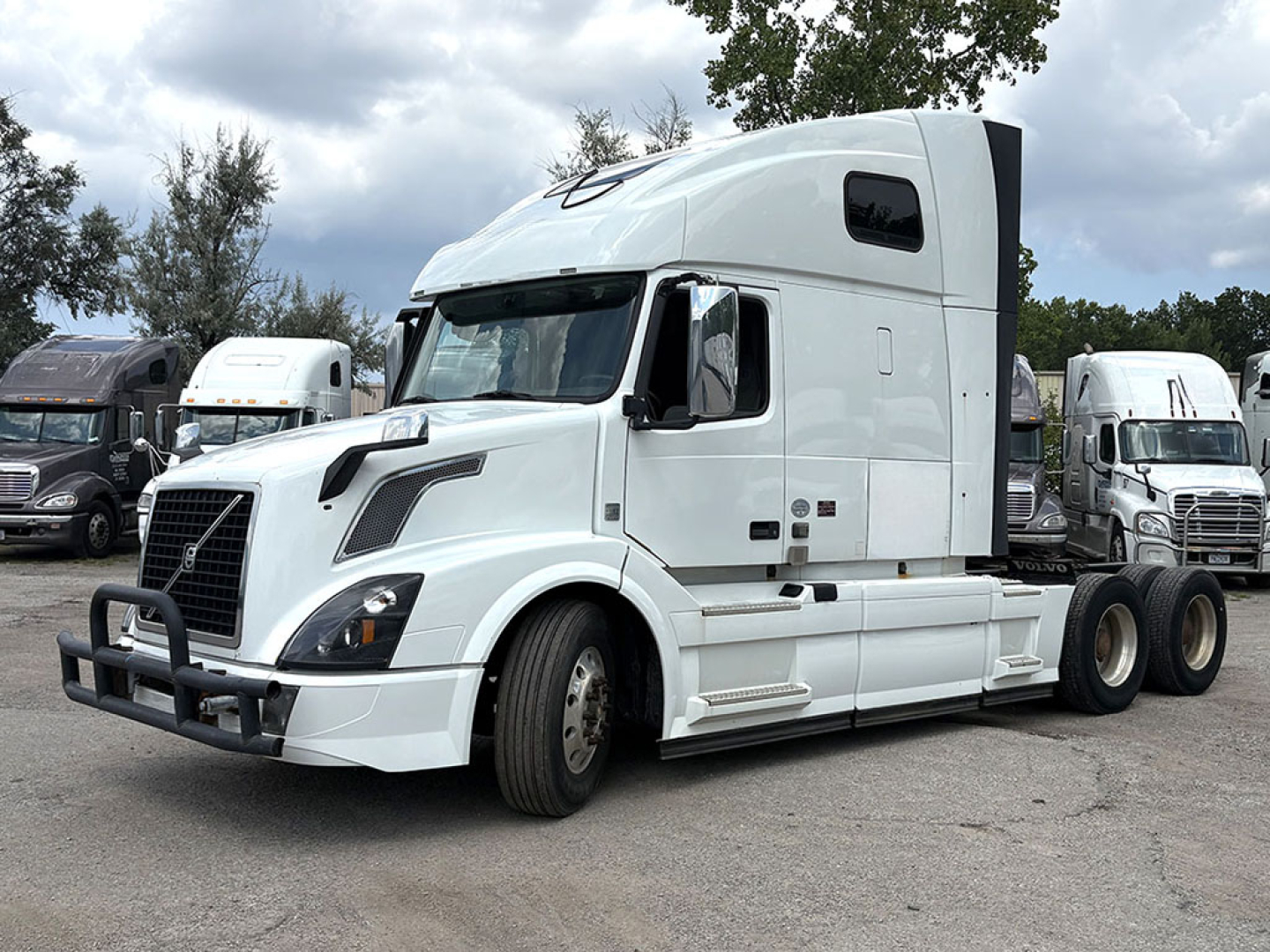 Volvo VNL 670 sleeper cab tractor in white with bumper guard, side mirrors, and large aerodynamic cab; visible front grille, headlights, and dual rear wheel configuration.